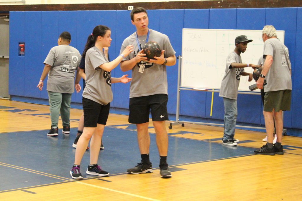 a coach is showing a female teenager how to throw a bowling ball