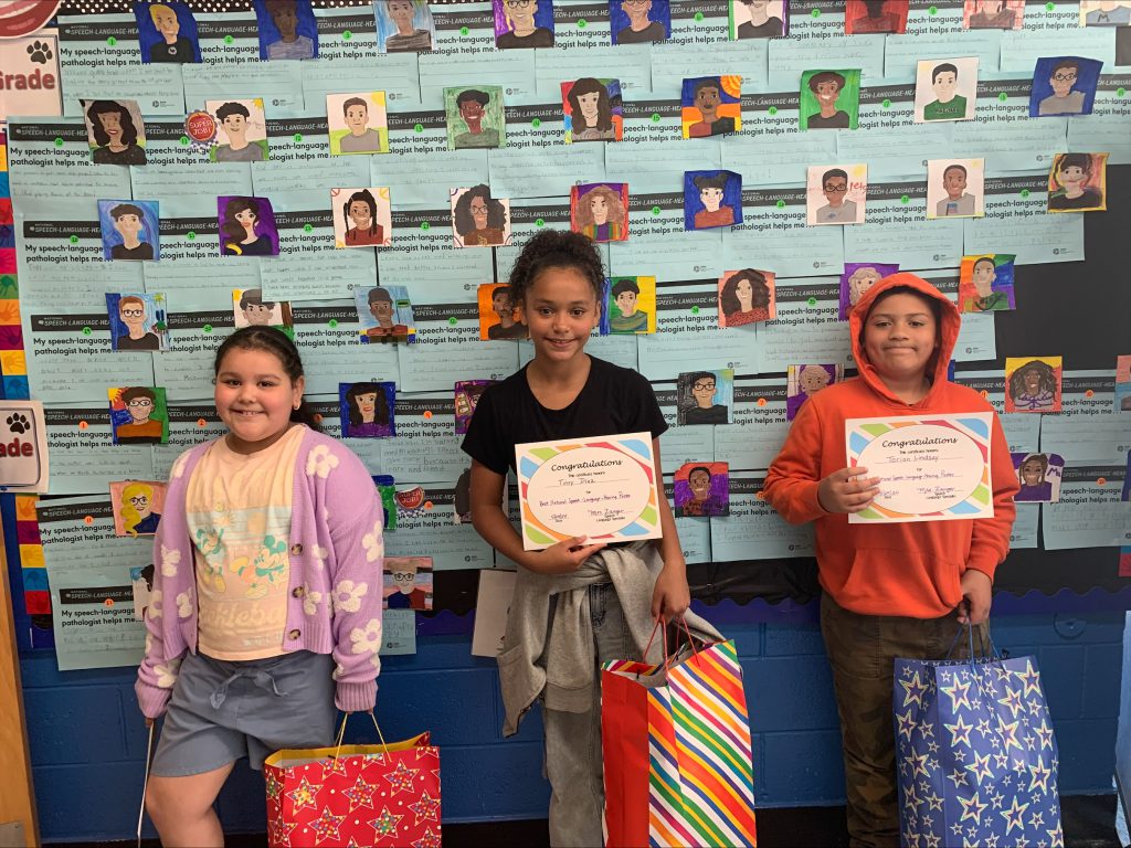 The three winners of the speech poster pose next to their creations 