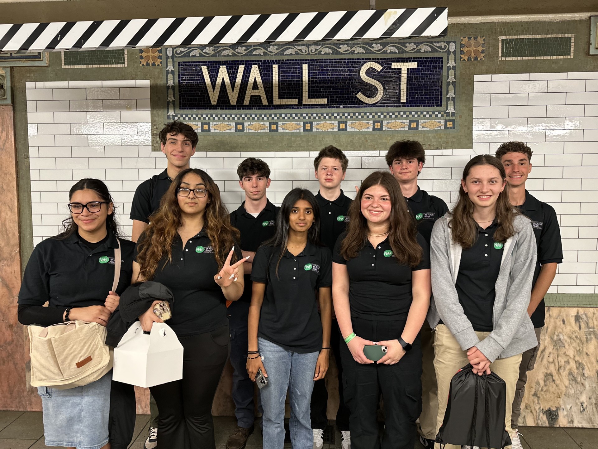 a group of Academy of Finance students are posing in the Wall Street subway station 