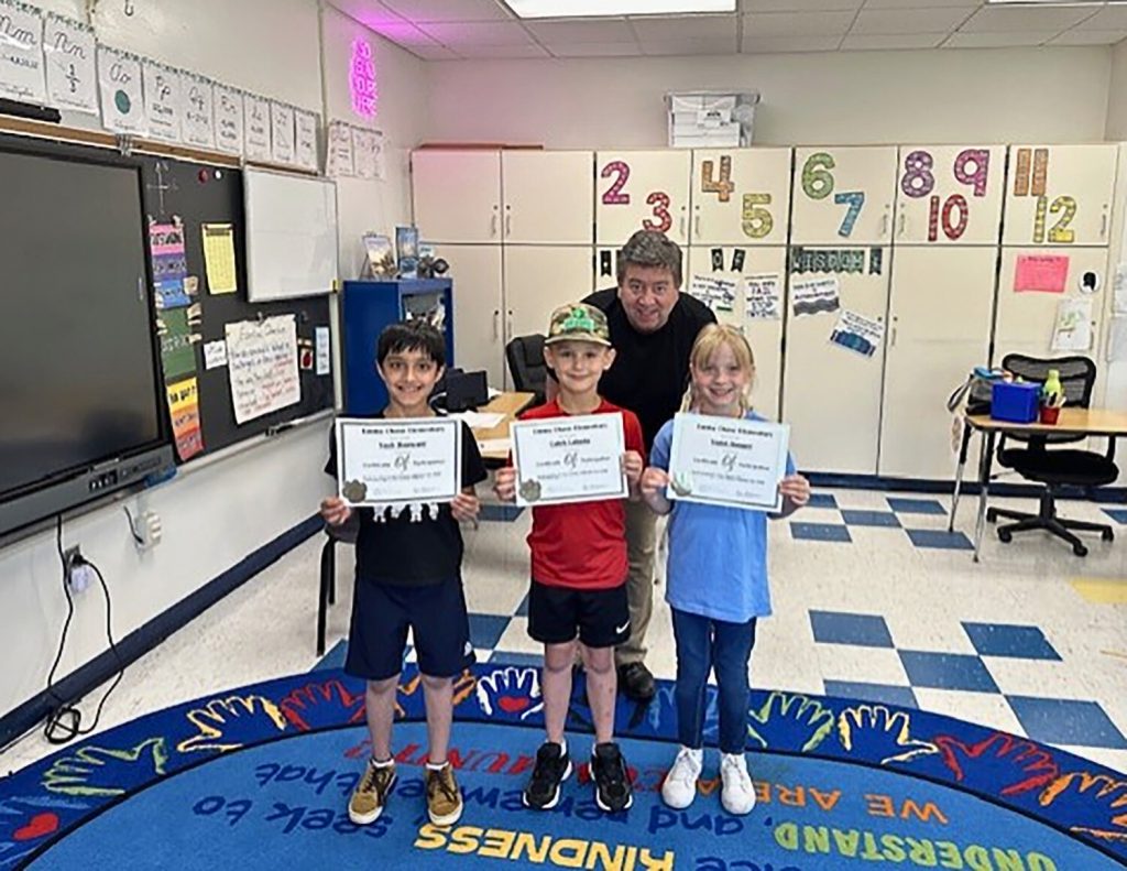 Principal with three elementary students holding certificates. 