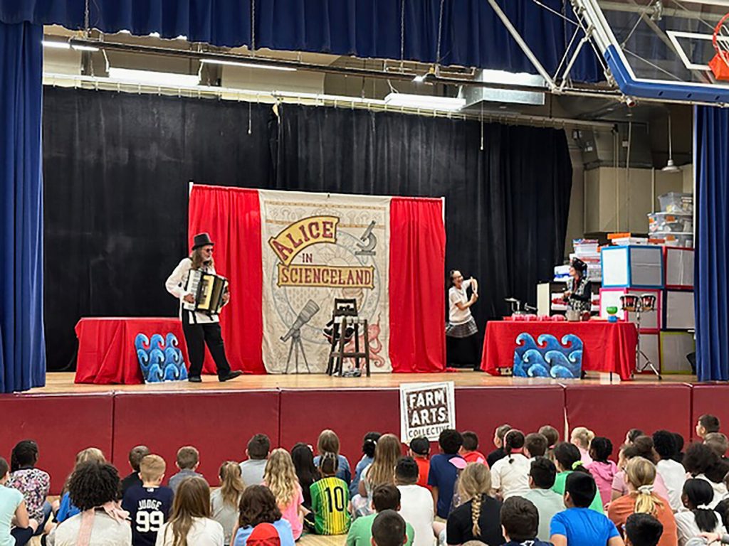 Three performers on stage presenting "Alice in Scienceland."