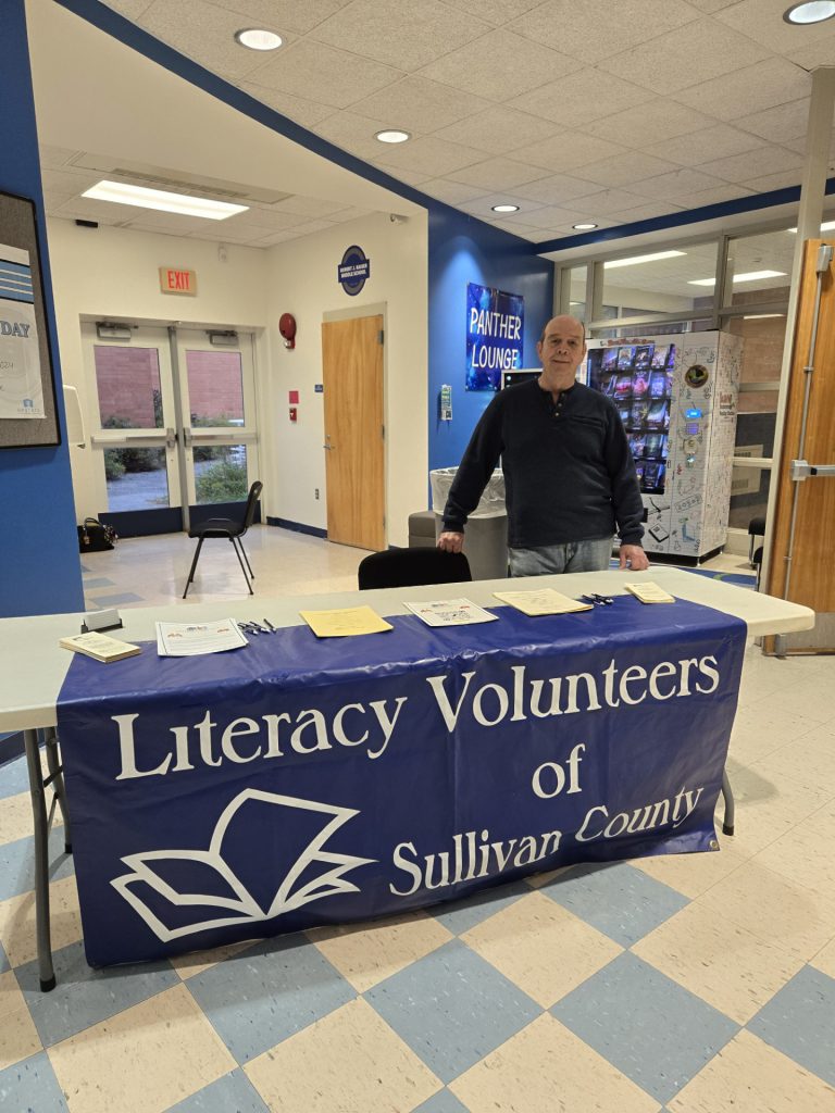 Al Feller, Literacy Volunteers of Sullivan County is posing behind a table 