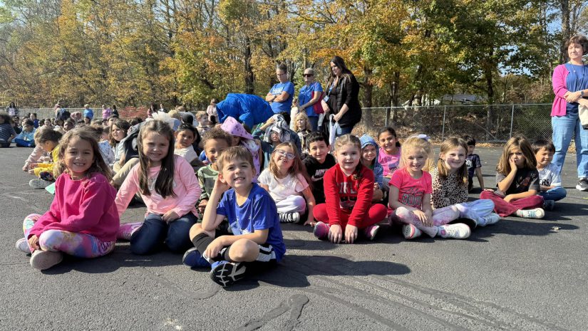 a group of young students are seated outside smiling for the camera