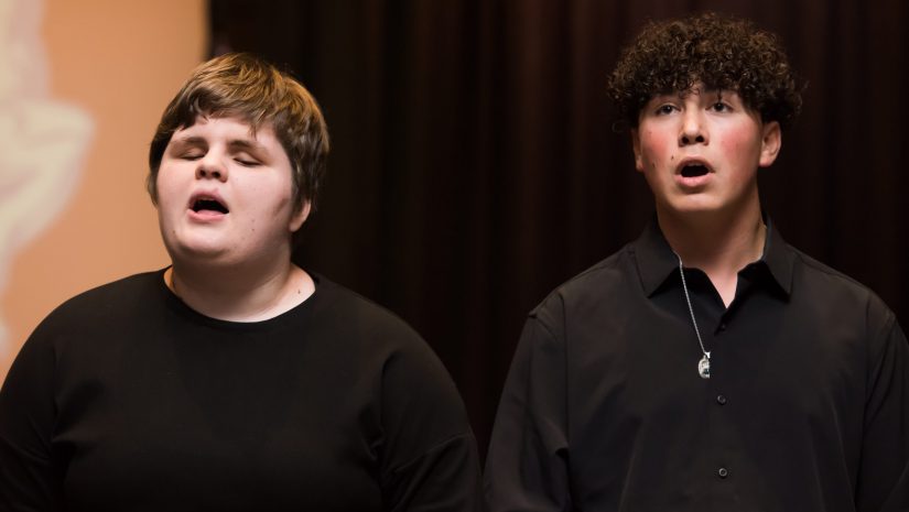 two students are singing during a performance