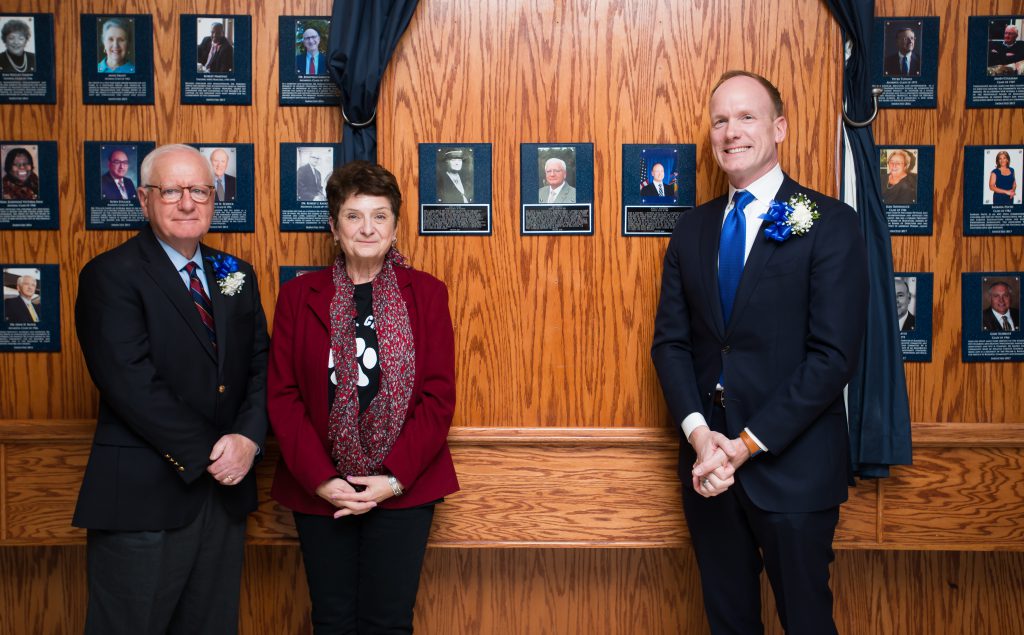 the three Hall of Distinction inductees are posing near their plaques 