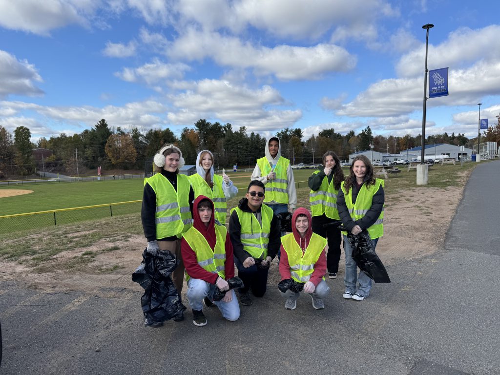 litterpluck volunteers are posing near the football field. They are all wearing reflective vests.