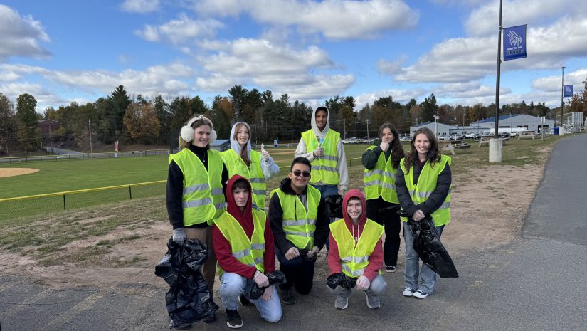 litterpluck volunteers are posing near the football field. They are all wearing reflective vests.