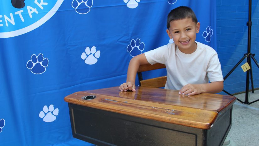 a young student is seated at a desk smiling