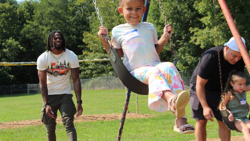 a father is pushing his daughter on a swing