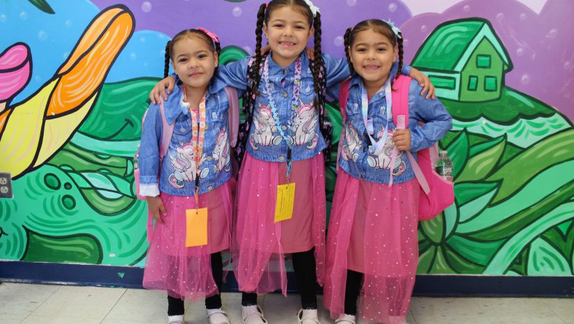 three students in matching outfits are posing and smiling