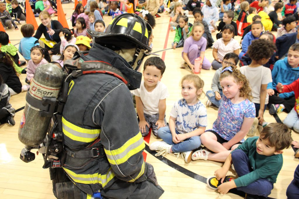 a firefighter is surrounded by a group of students 