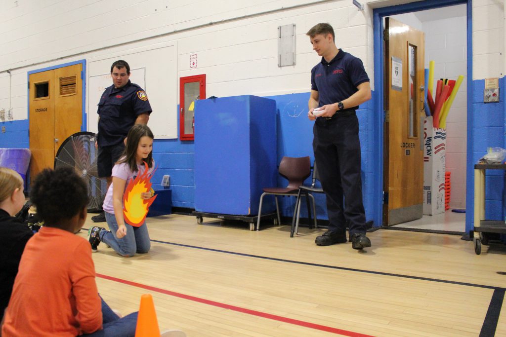 a young girl is demonstrating how to stop drop and roll