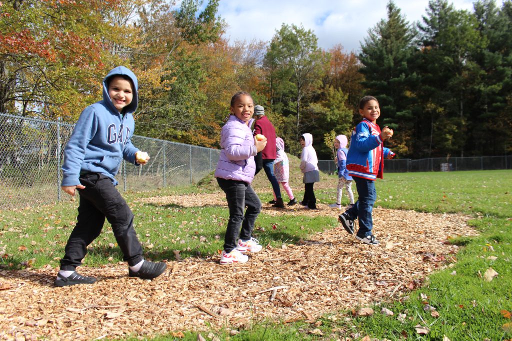 Three students are walking down a path smiling. 