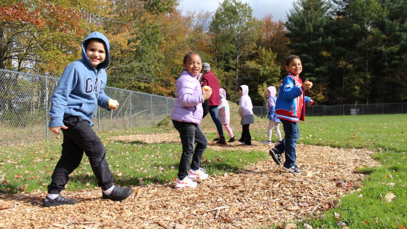 Three students are walking down a path smiling.