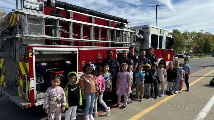 a group of firefighters are posing in front of a firetruck with a class of young students