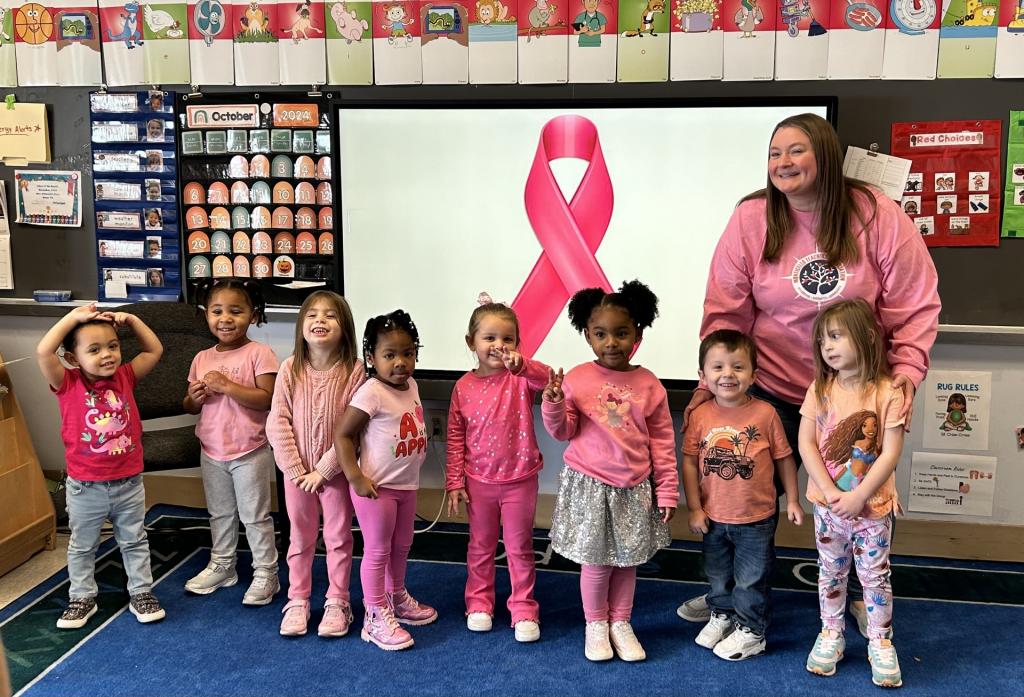 students are dressed in pink and posing with their teacher