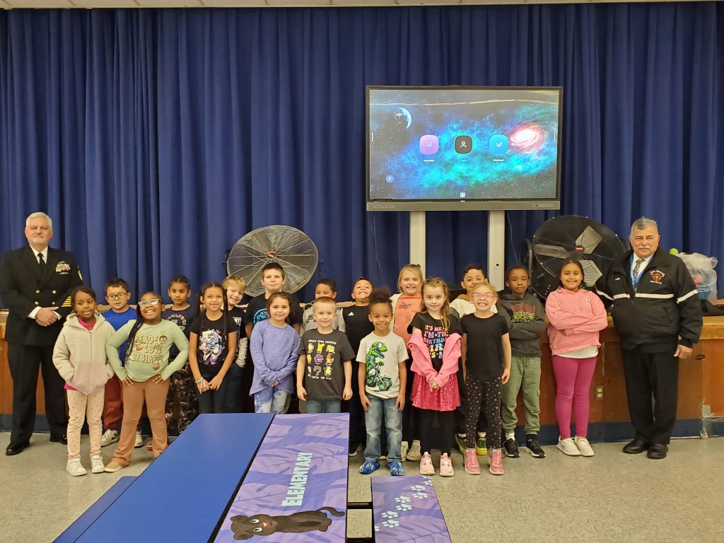 a group of children pose with veterans 