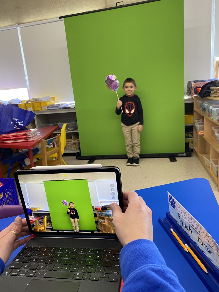 A student is posing in front of a green screen with a balloon