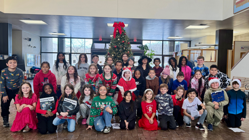 a group of students are posing in front of a christmas tree wearing holiday-themed outfits