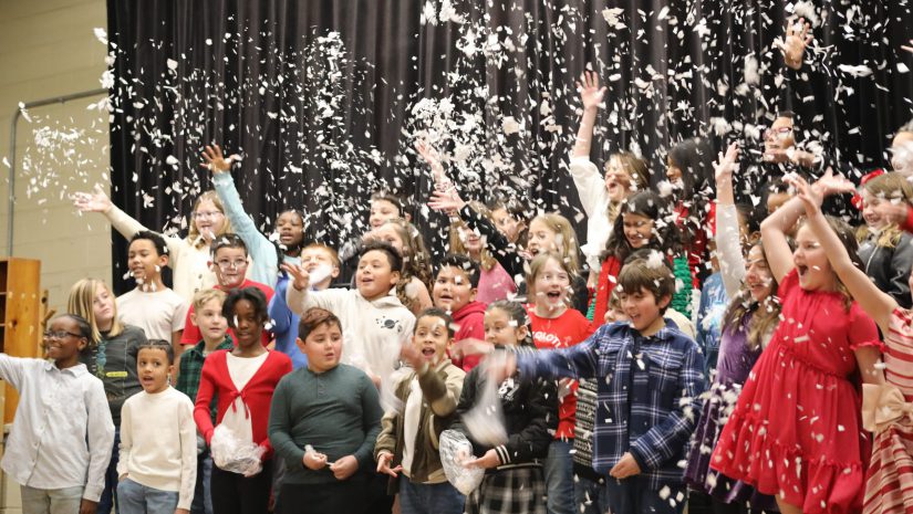 students are throwing white confetti into the air in the middle of a chorus performance.