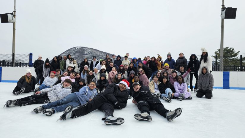 a group of students wearing ice skates are posing in the middle of an ice skating rink