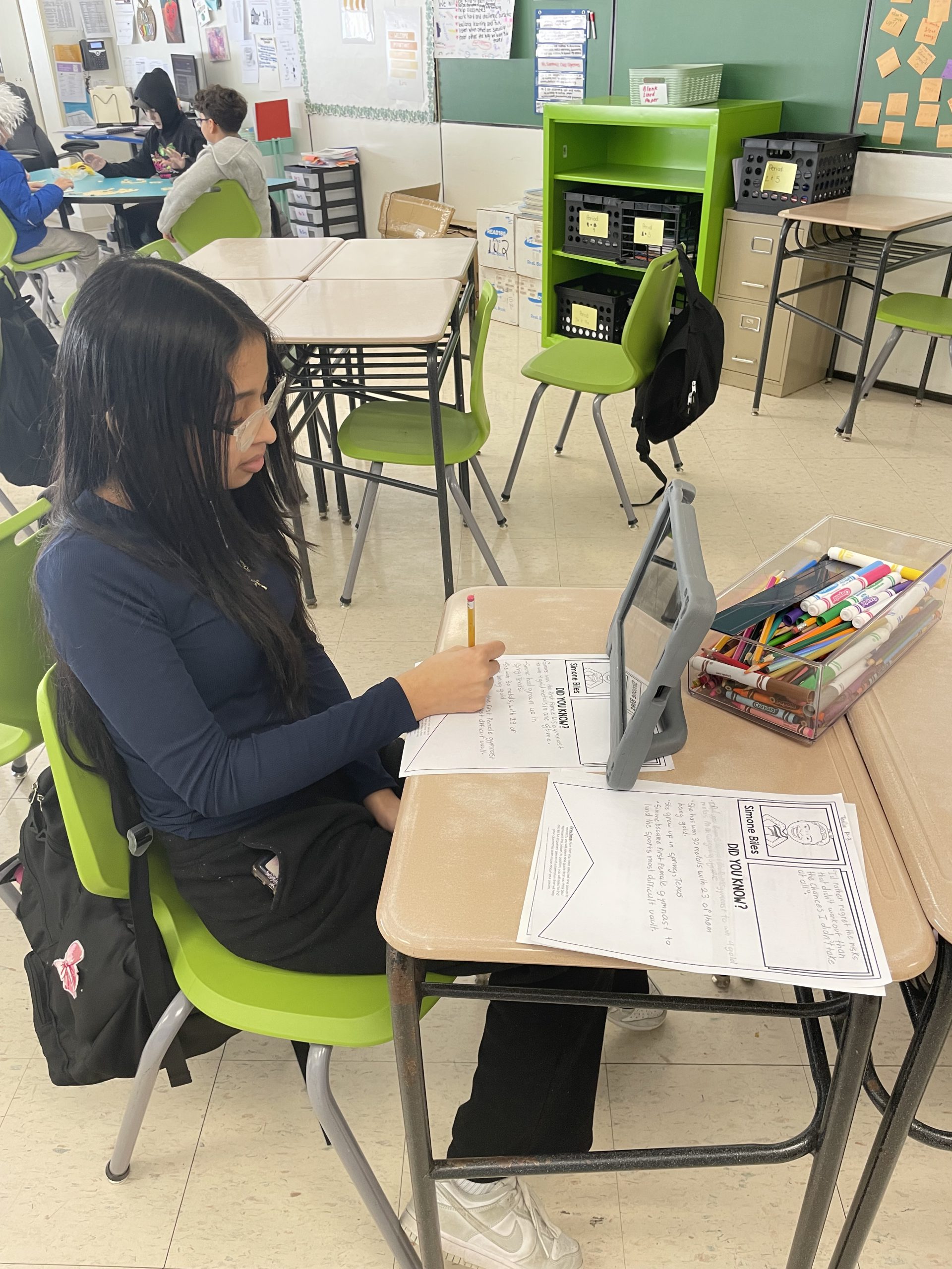 a student is seated at a desk working on a black history project. 