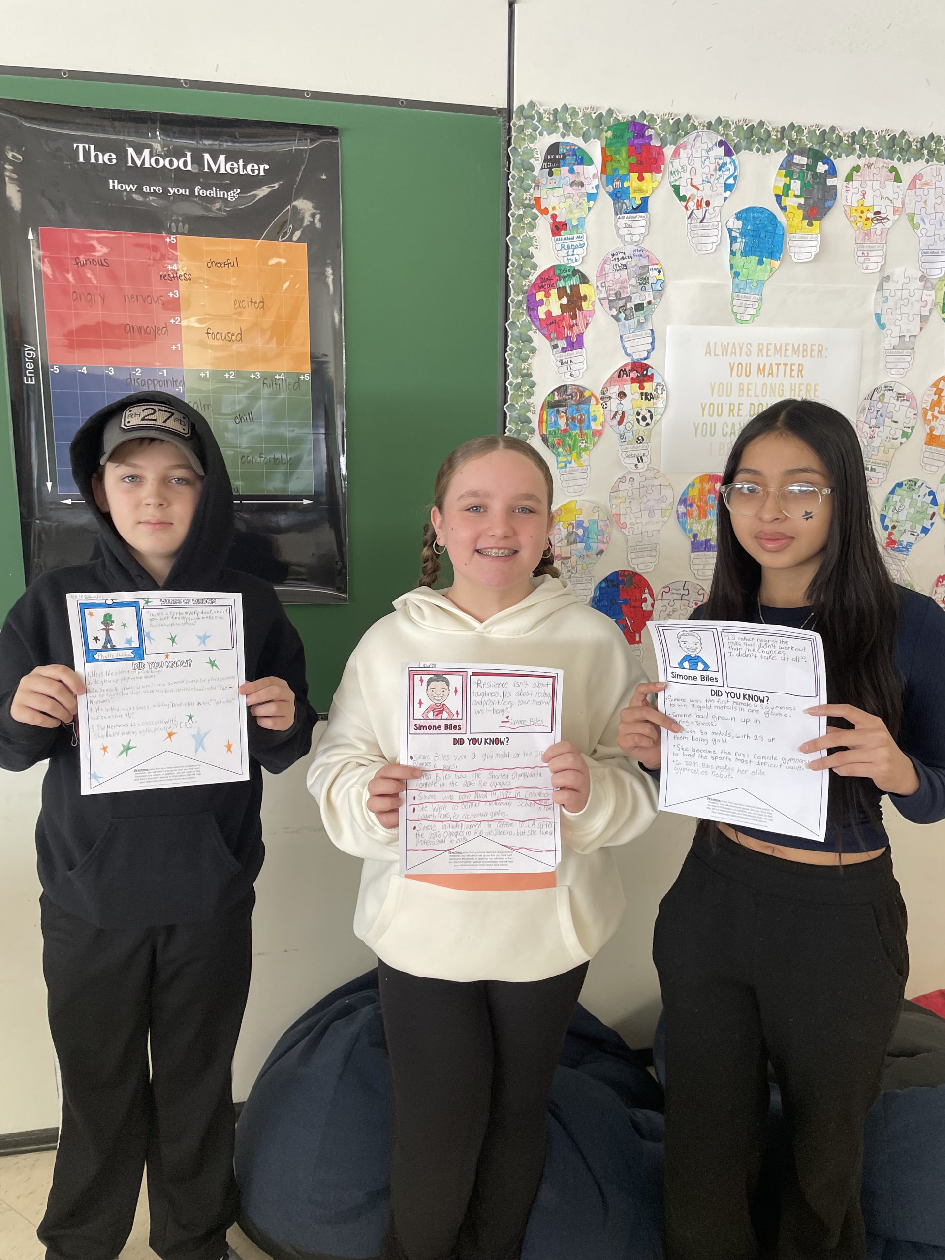 three students pose holding up the projects they've been working on