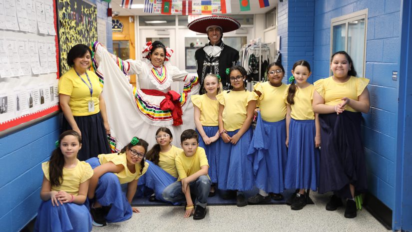 student dancers pose with dancers in traditional Mexican costume.