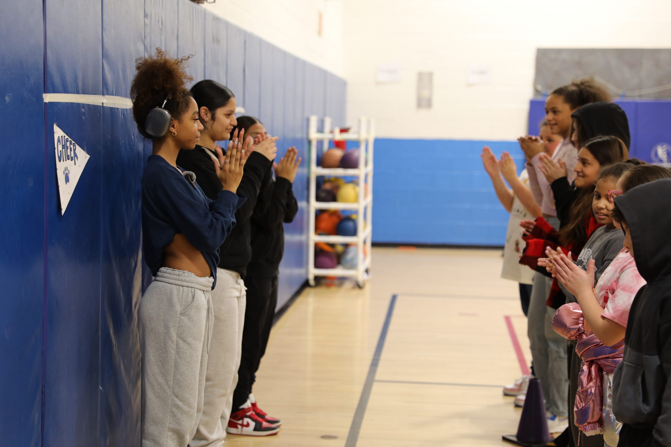 high school cheerleaders are demonstrating a dance to the younger students. 