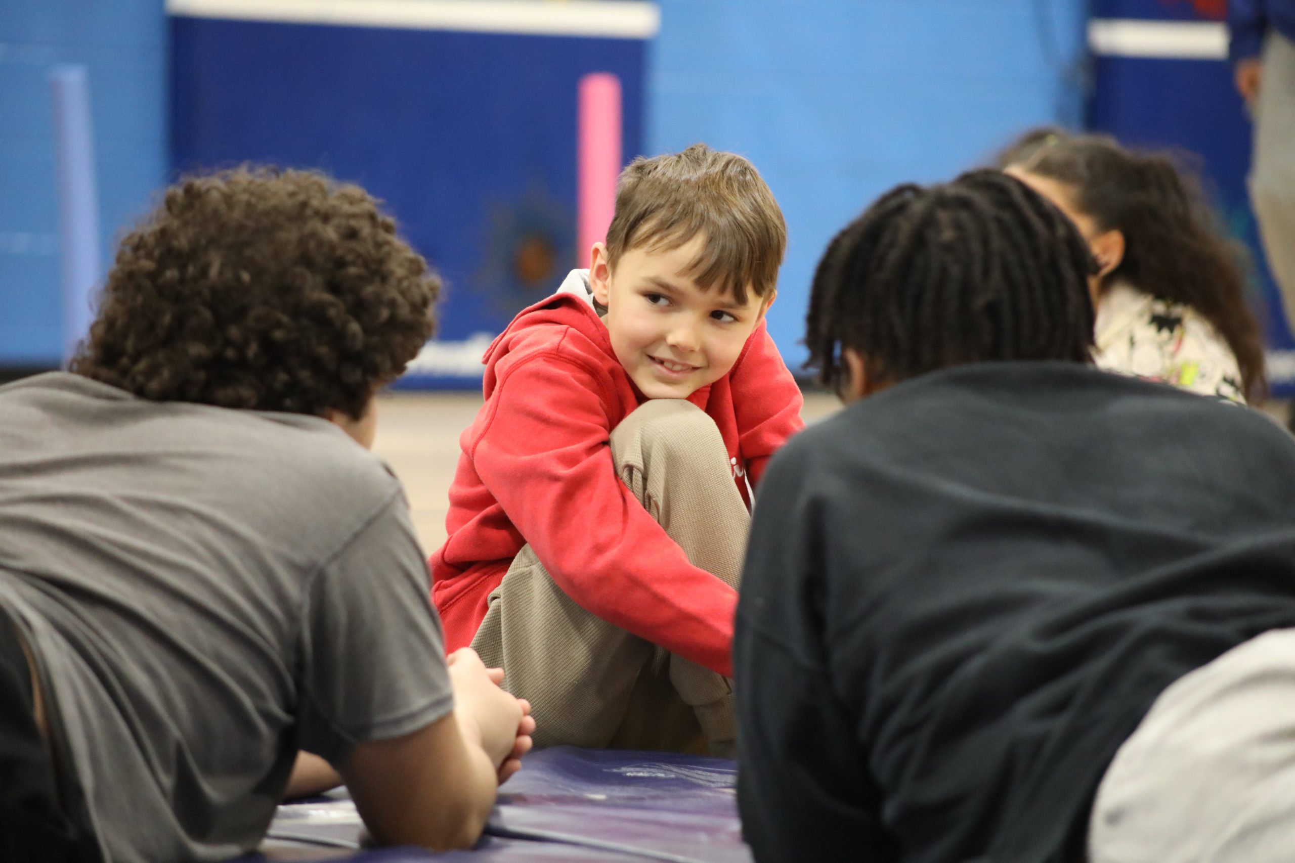 two older students are in the middle of speaking to a younger student who is looking up at them with admiration