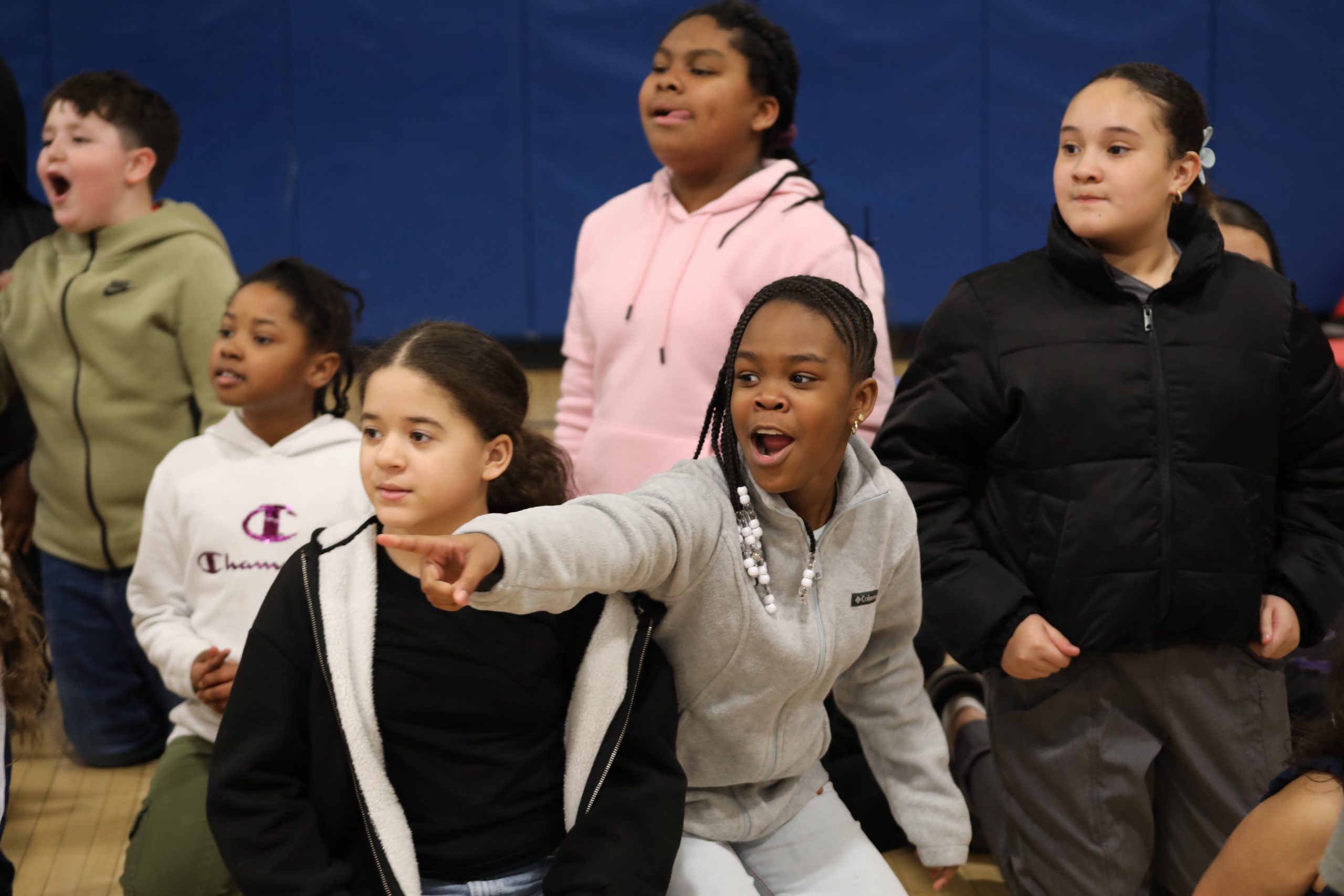 elementary school students are in a group cheering.