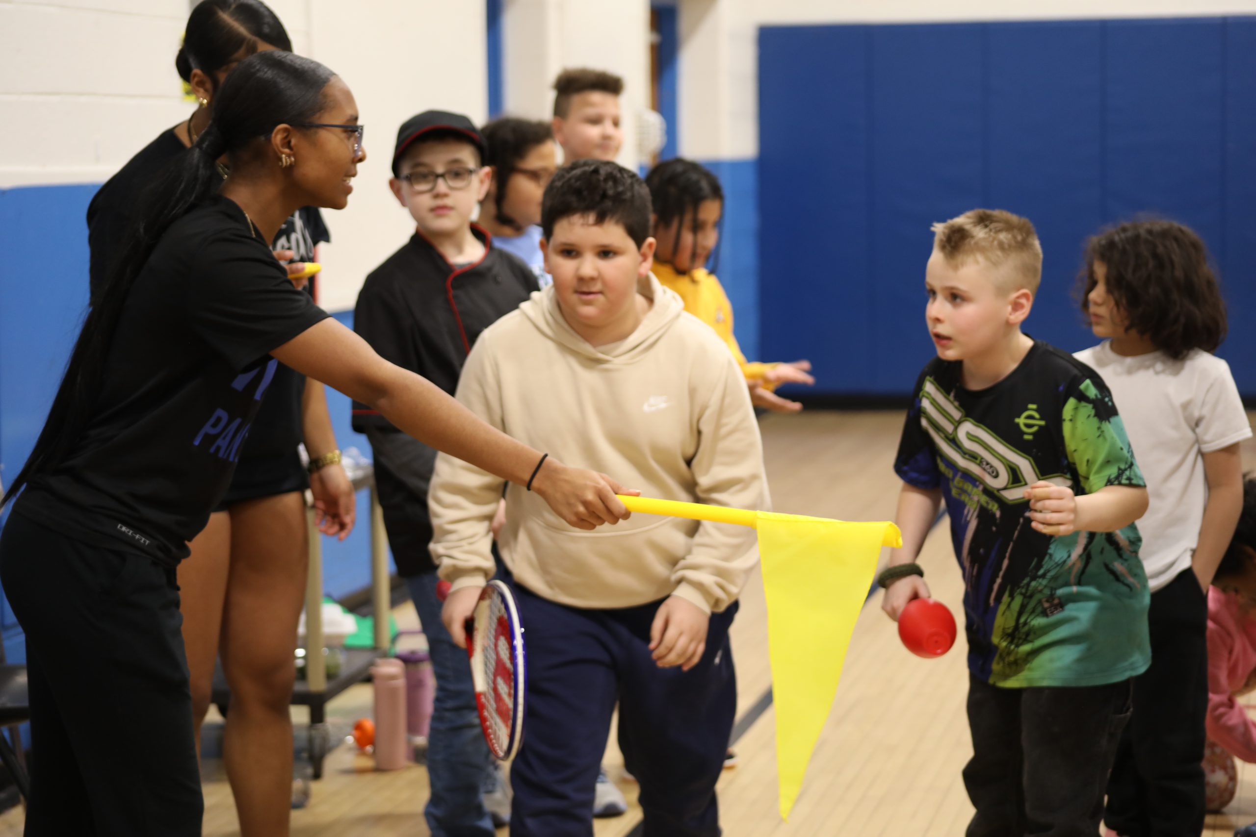 two students are lined up to begin a race. An older student is holding a flag, about to start the race 