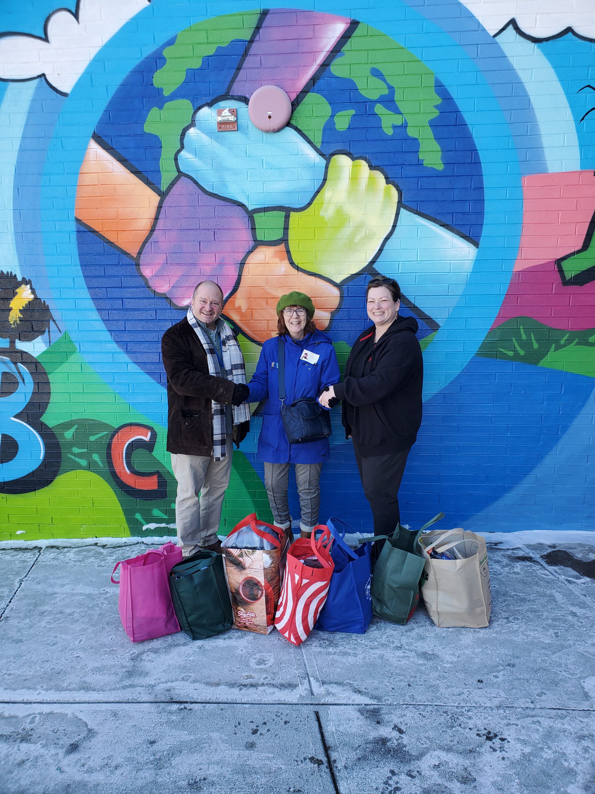  representatives of Wolf Lake Neighbors Association pose with Cooke staff in front of bags of donated items. 