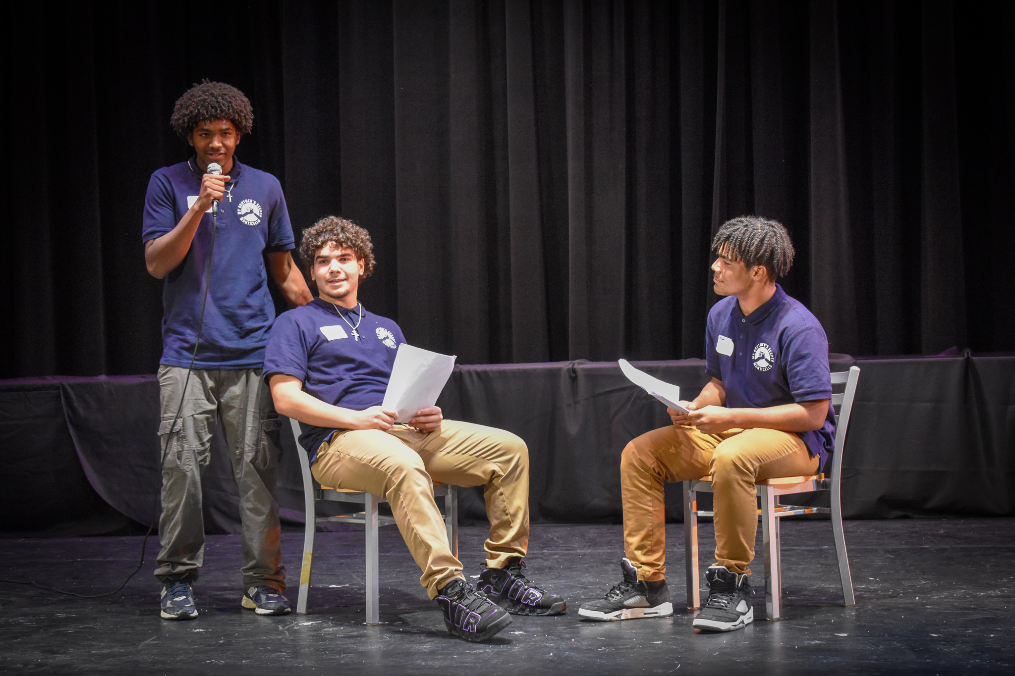 three students are on stage in the middle of a performance